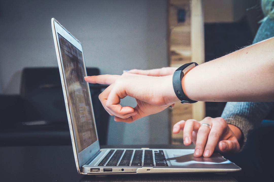 Two people pointing at a laptop, discussing the benefits of enterprise search.